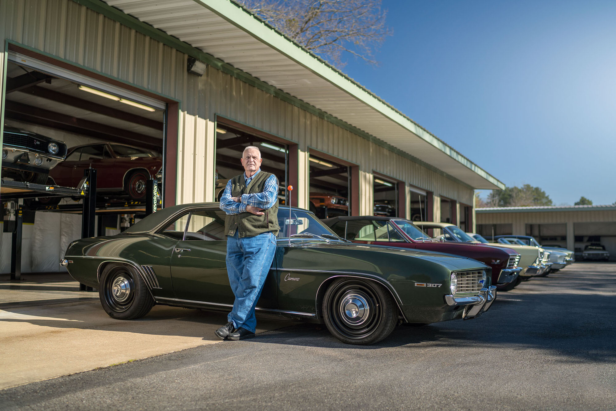 George Poteet posing in front of his classic cars at his home Mississippi garage. Photographed for Car And Driver Magazine.