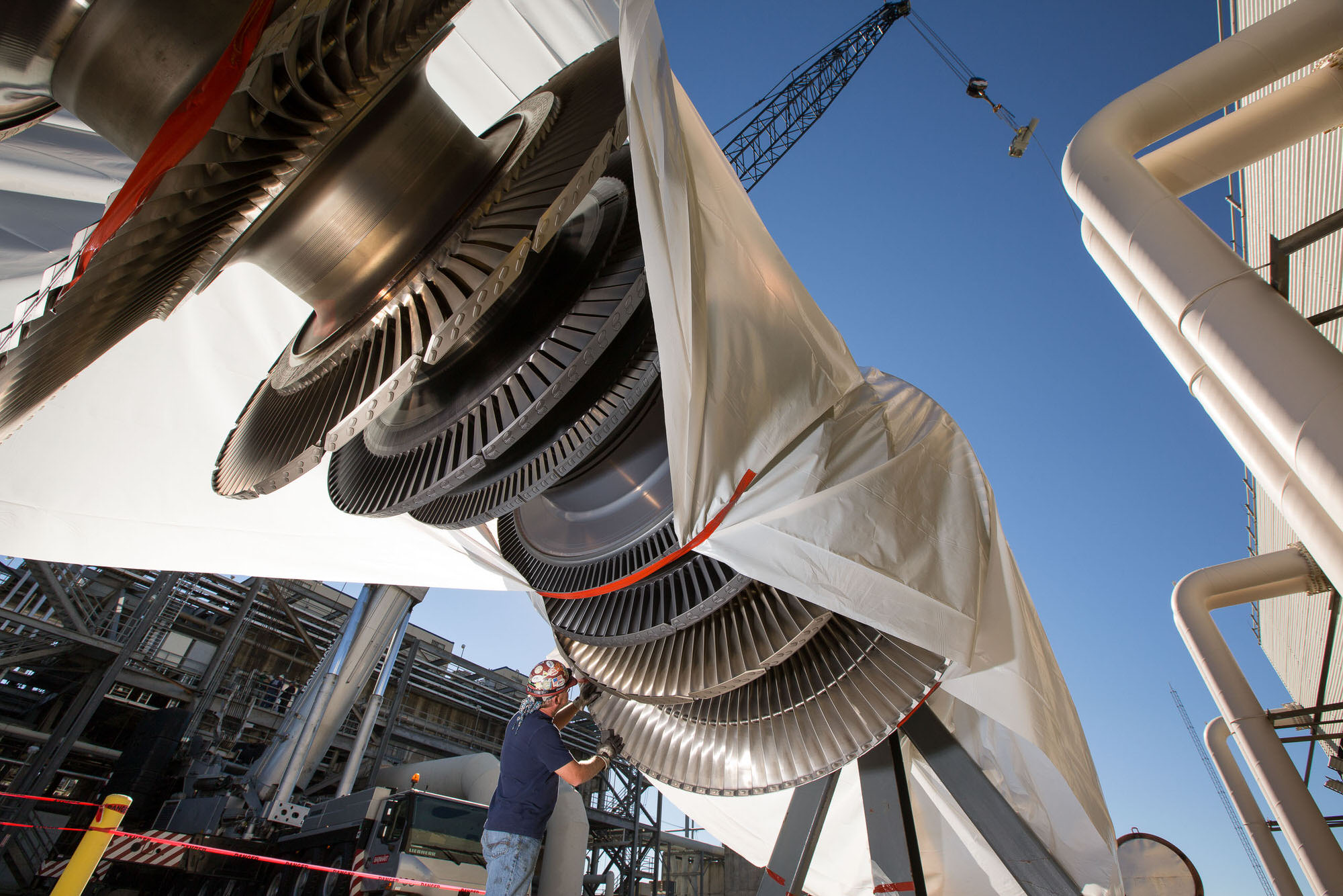 Worker inspecting GE gas turbine for installation at Alabama facility.