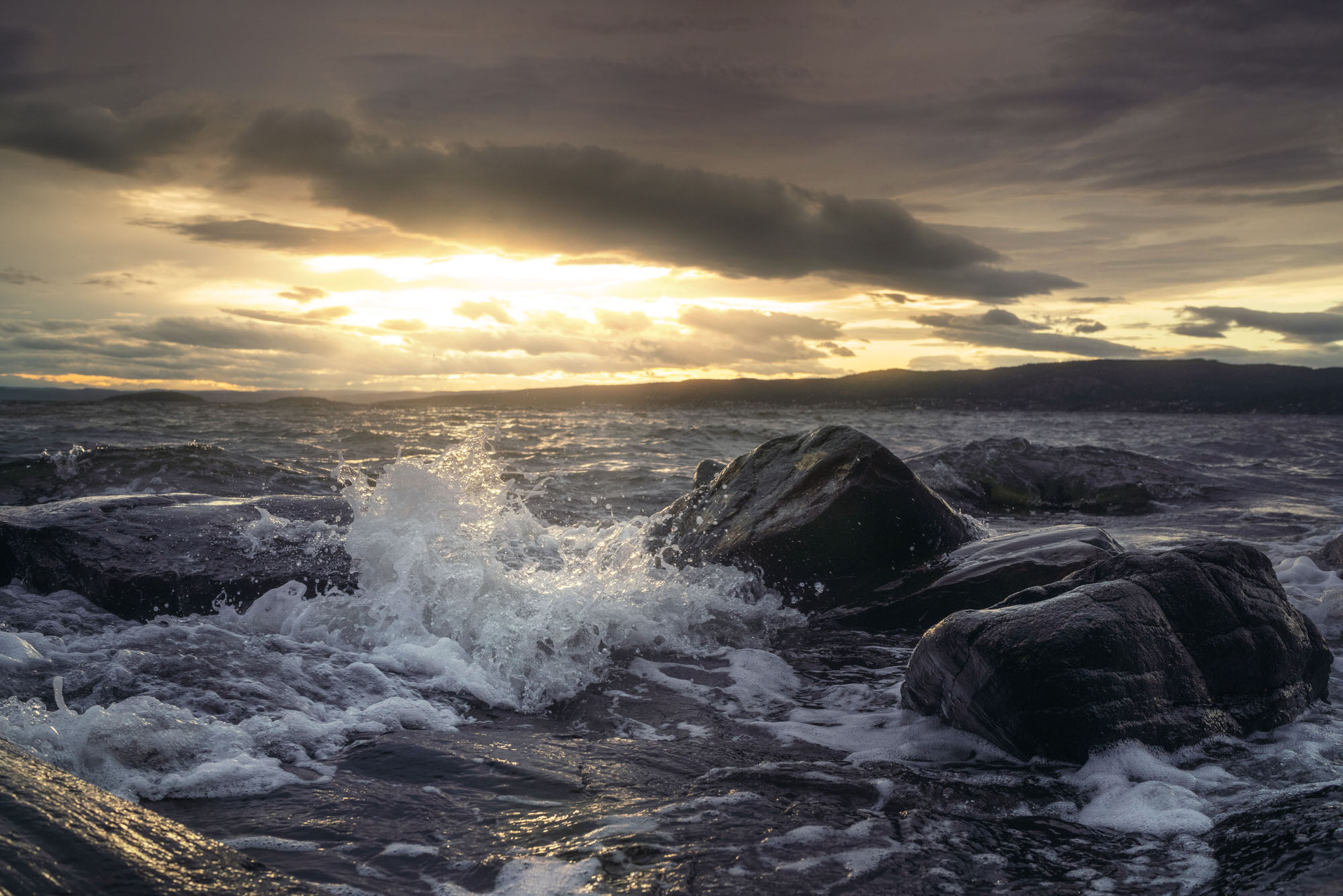 Waves crashing on the rocks of Son, Norway during sunset